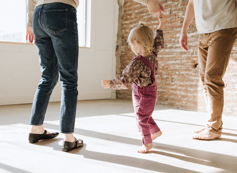 a mom and dad dance with their two year old daughter during a family photo session in Des Moines Iowa photographed by Haverlee Photography