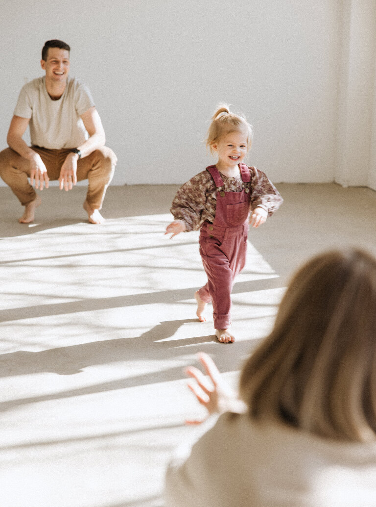 a two year old girl runs toward her mom at East Fifth Studio in downtown Des Moines during a session with Haverlee Photography 