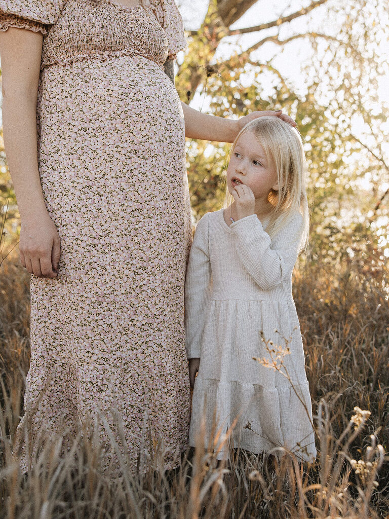 Mom standing in long floral print dress with daughter in white dress at Saylorville Lake family session by Asheville Family Photographer Haverlee Photography